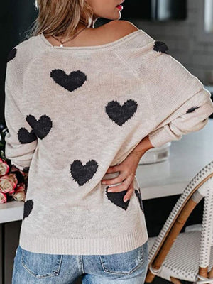 Eggshell raglan knit sweater with black heart motif, crew neck, and long sleeves.