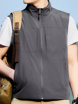 Grey zip up vest with stand collar and zippered pockets, worn by a man.