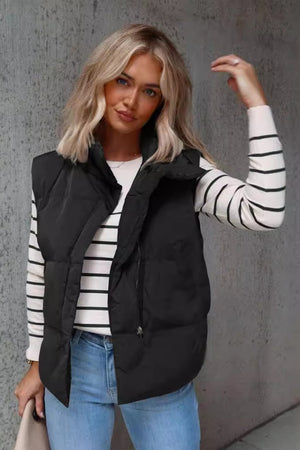 Black padded stand collar vest with zipper closure, styled with a striped long sleeve shirt and jeans.