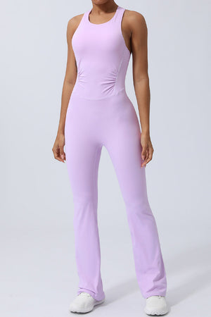 Blush pink cross-back flare leg unitard with ruched sides and a racerback detail.