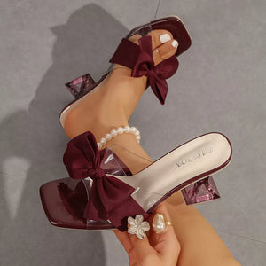 Burgundy open-toe sandals with clear straps and a large bow detail.