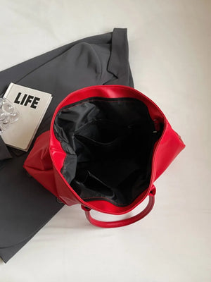 Scarlet tote bag with open top and interior pockets, next to a book and blazer.