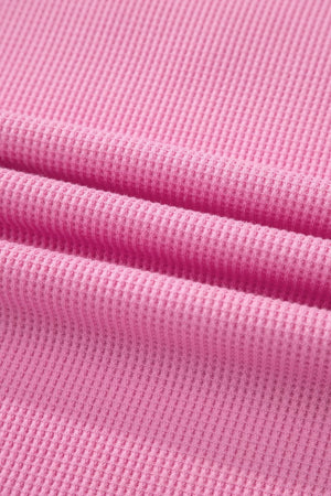 Pink waffle knit polyester t-shirt with a pocket detail and textured fabric.