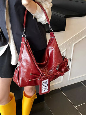 Red shoulder bag with braided strap and tassel details
