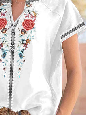 White floral embroidered notched blouse with short sleeves and lace trim.