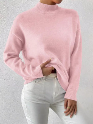 Pink mock neck knit sweater with dropped shoulders, styled with white jeans.
