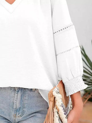 White long sleeve blouse with smocked cuffs and lace trim detail.