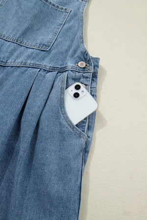 Denim jumpsuit with wide legs, pleats, and a pocket holding a smartphone.