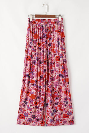 Painterly floral palazzo trousers in strawberry pink with a vibrant, colorful bloom print and wide leg.