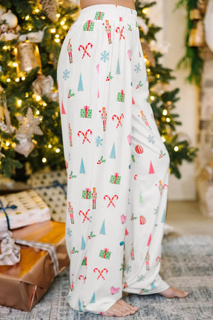 White pajama pants with festive Christmas print, featuring nutcrackers, candy canes, and gifts.
