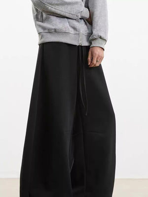 Black wide-leg sweatpants with drawstring waist, shown with a grey zip-up hoodie.