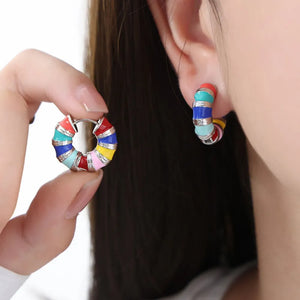 Rainbow enamel segmented hoop earrings with silver accents, worn by a model.