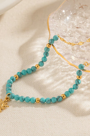 Gold celestial sunburst beaded necklace with turquoise beads and gold accents.
