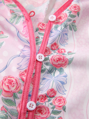 Pink floral and bow print maternity shirt with button-up closure and ruffled trim.