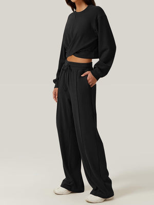 Black cross-front knit lounge top with crew neck and long sleeves, paired with wide-leg sweatpants.
