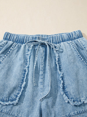Light wash denim shorts with elastic drawstring waist and frayed pocket details.