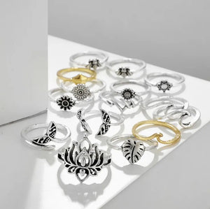 Silver alloy ring stack with botanical and sculptural designs, including lotus, leaf, and sun motifs.