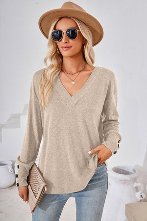 Button-cuff slouch v-neck top in cream with button details on sleeves.