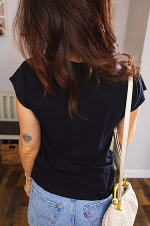 Black polyester V-neck tee with cutout detail and short sleeves, styled with jeans.