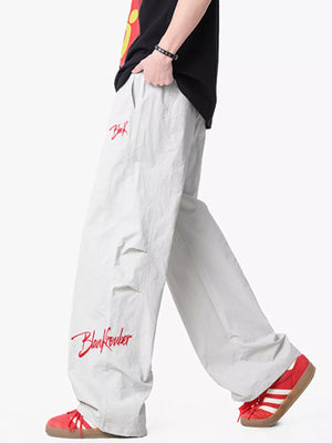 Lightweight wide-leg pants in light gray with red embroidered logo detail and drawstring waist.