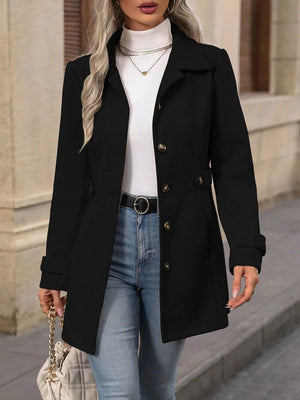 Black button-up trench coat with cinched waist and gold buttons, worn with jeans.