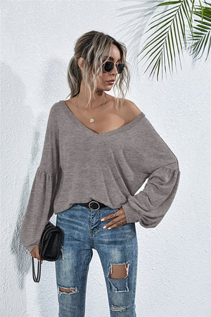 Off-shoulder knit top in dark gray with blouson sleeves and a V-neck.