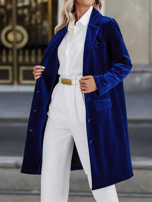 Elegant longline trench coat in deep teal velvet with lapel collar and buttoned front.