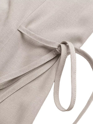 Midi dress in light beige with adjustable side ties and button detail.