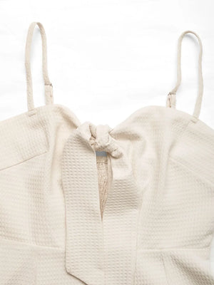 Beige textured romper with tie-front detail and smocked bodice.