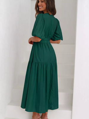 Green midi dress with puff sleeves, cinched waist, and tiered skirt.