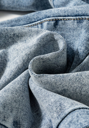 Cuffed hem washed denim trousers in medium acid wash with visible stitching detail.