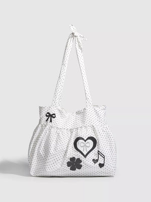 White polka dot canvas shoulder bag with heart, bow, clover, and music note appliqués.