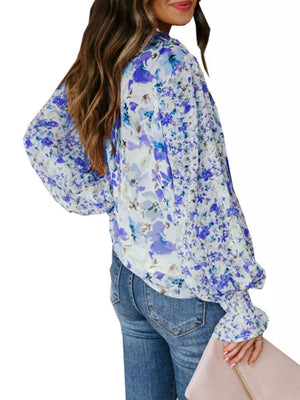Blouse with blue and purple floral print, long balloon sleeves, and smocked cuffs.