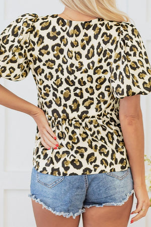 Leopard print peplum blouse with puff sleeves and cinched waist detail.