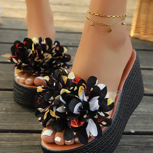 Floral pom-pom wedge sandals with clear straps and a multicolor floral pattern.