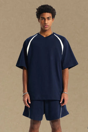 Navy V-neck raglan tee with white contrast trim on sleeves and neckline.