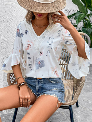 White floral bell sleeve blouse with lace trim and V-neck.