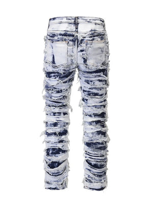 Distressed shredded denim jeans in medium sculptural wash with artistic rips and fraying.