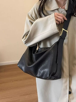 Black leather shoulder bag with adjustable strap and gold buckle detail.