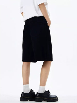 Black chino shorts with drawstring waist and pockets, styled with white socks and black shoes.
