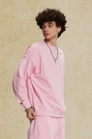 Oversized crewneck sweatshirt in blush pink with subtle shoulder detail and relaxed fit.