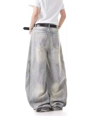 Men's light wash baggy jeans with a belted waist and distressed details.