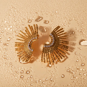 Gold sunburst crystal earrings with textured rays and a sparkling crystal arc.