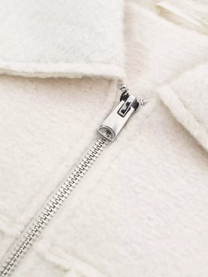 White cropped zip-up jacket with textured fabric and silver zipper detail.