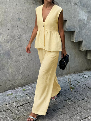 Yellow peplum hem two-piece set with button detail, V-neck sleeveless top and wide-leg pants.