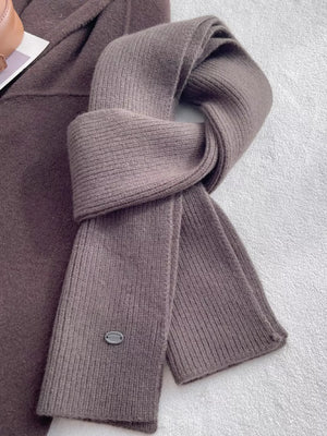 Gray brown ribbed knit wool scarf with a subtle texture detail and a small logo tag.