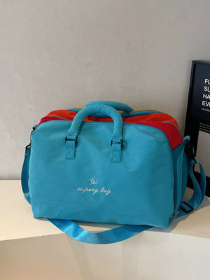 Blue duffel bag with embroidered text and colorful accents, featuring top handles and a shoulder strap.