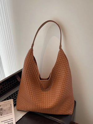 Brown woven straw tote bag with a textured finish and leather strap.