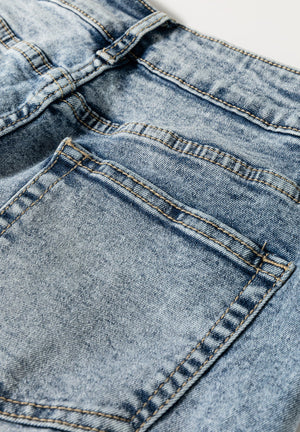 Cuffed hem washed denim trousers in medium acid wash with visible stitching details.