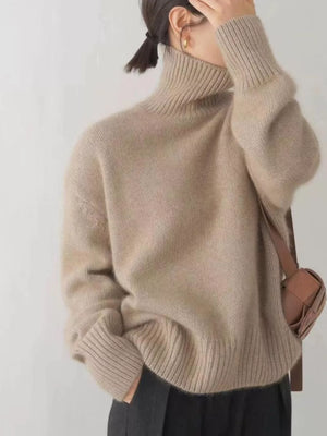 Beige acrylic turtleneck sweater with dropped shoulders and ribbed cuffs and hem.